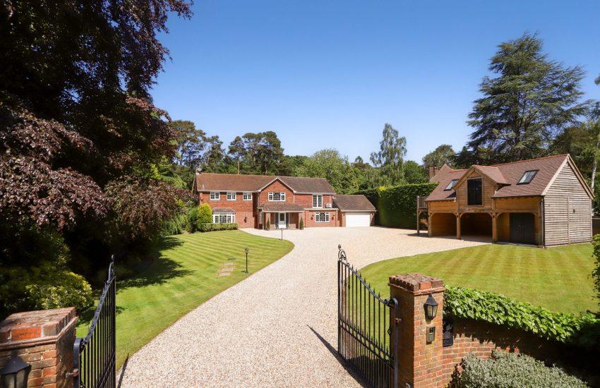A detached Surrey family home set back behind gates, with a gravel driveway and landscaped gardens
